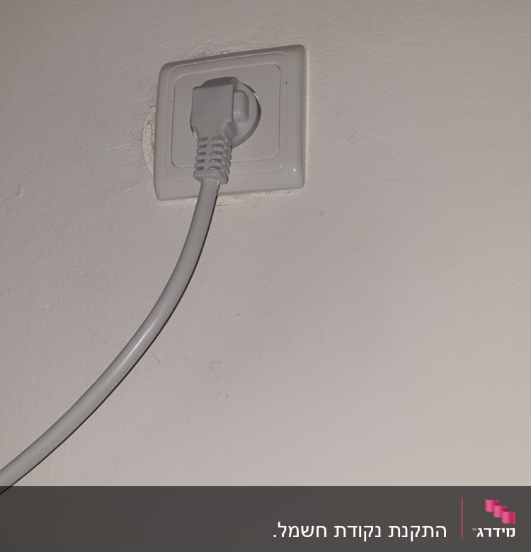 שקע חשמל עם תקע מחובר לקיר לבן